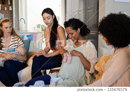 Expectant mother surrounded by friends celebrating baby shower at home Expectant mother surrounded by friends celebrating baby shower at home 135676579