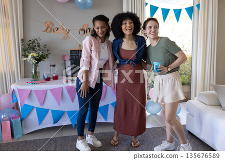 Celebrating baby shower, friends smiling and posing in decorated living room together Celebrating baby shower, friends smiling and posing in decorated living room together 135676589