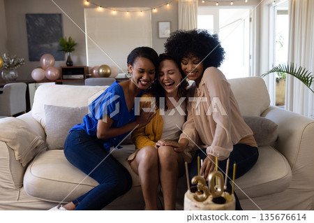 Friends celebrating 30th birthday at home, laughing and enjoying cake together 135676614