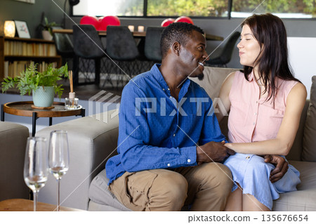 Couple sitting on sofa at home, smiling and enjoying quality time together Couple sitting on sofa at home, smiling and enjoying quality time together 135676654