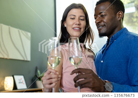 Couple celebrating at home, toasting with champagne glasses and smiling warmly Couple celebrating at home, toasting with champagne glasses and smiling warmly 135676673