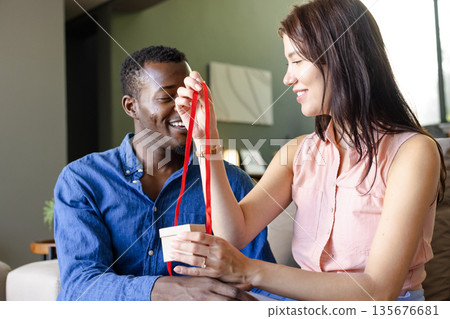 Couple exchanging gifts at home, smiling and enjoying joyful moment together 135676681