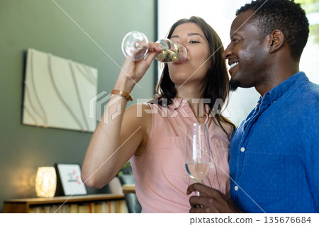 Couple enjoying wine together at home, celebrating with joyful expressions 135676684