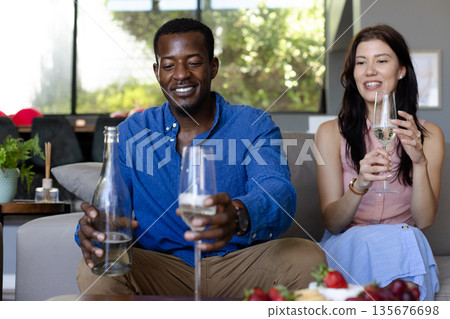 Friends enjoying wine and conversation at home, celebrating with smiles and laughter Friends enjoying wine and conversation at home, celebrating with smiles and laughter 135676698