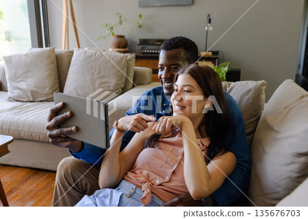 Couple relaxing at home, smiling and taking selfie with tablet on couch Couple relaxing at home, smiling and taking selfie with tablet on couch 135676703