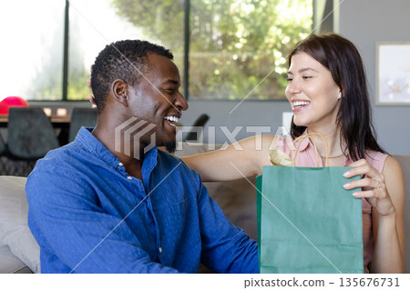 Couple exchanging gifts at home, smiling and enjoying joyful moment together 135676731