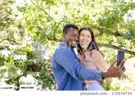 Couple taking selfie outdoors, smiling and enjoying sunny day in nature 135676739