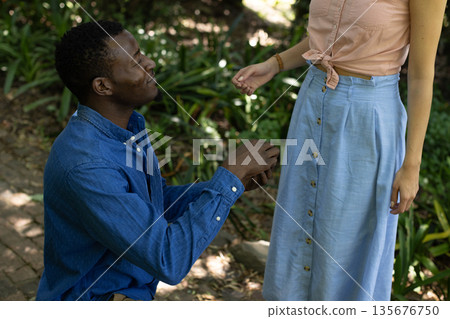 Man proposing to woman in park, holding ring and smiling with joy Man proposing to woman in park, holding ring and smiling with joy 135676750