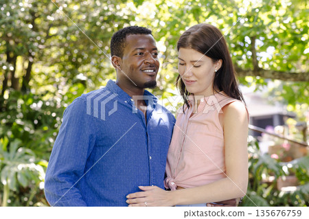 Couple embracing outdoors, smiling and enjoying sunny day in park Couple embracing outdoors, smiling and enjoying sunny day in park 135676759