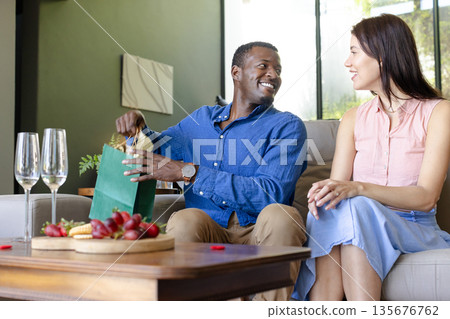 Couple exchanging gifts at home, smiling and enjoying cozy celebration Couple exchanging gifts at home, smiling and enjoying cozy celebration 135676762