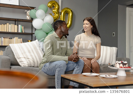 African American man and woman celebrating birthday at home with balloons and cake 135676801