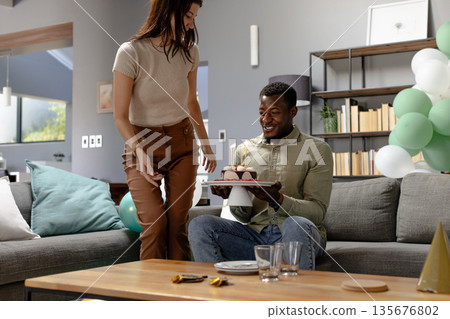 Celebrating at home, African American man receiving birthday cake with joy 135676802
