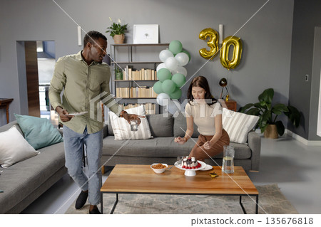 Celebrating 30th birthday, friends enjoying cake and snacks in cozy living room Celebrating 30th birthday, friends enjoying cake and snacks in cozy living room 135676818