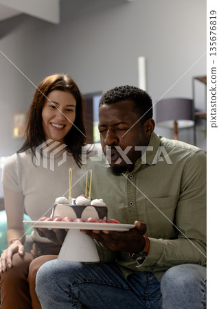 Blowing candles on cake, African American man celebrating birthday with woman Blowing candles on cake, African American man celebrating birthday with woman 135676819