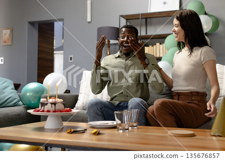 Surprised by birthday cake, African American man celebrates with smiling woman at home Surprised by birthday cake, African American man celebrates with smiling woman at home 135676857