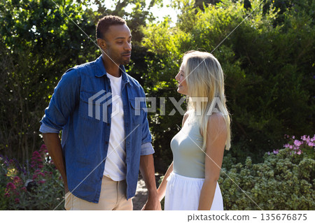 Couple enjoying romantic moment in garden, holding hands and smiling warmly 135676875
