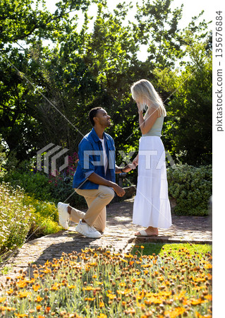 Man proposing to surprised woman in beautiful garden surrounded by flowers Man proposing to surprised woman in beautiful garden surrounded by flowers 135676884