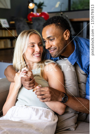 Couple relaxing on couch, smiling and enjoying quality time at home Couple relaxing on couch, smiling and enjoying quality time at home 135676913