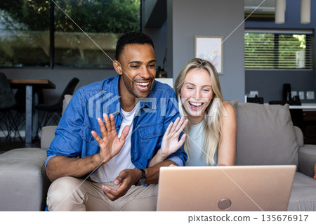 Happy couple video chatting on laptop at home, waving and smiling warmly 135676917