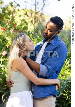 Couple embracing in garden, smiling and enjoying romantic moment together Couple embracing in garden, smiling and enjoying romantic moment together 135676922