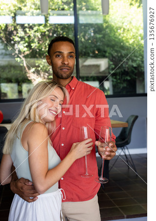Couple celebrating at home, holding champagne glasses and smiling warmly Couple celebrating at home, holding champagne glasses and smiling warmly 135676927