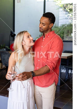 Couple celebrating at home, holding champagne glasses and smiling at each other Couple celebrating at home, holding champagne glasses and smiling at each other 135676931