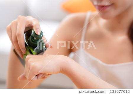 Closeup hands beautiful young woman applying lotion herb on hands looking mirror at home. 135677013