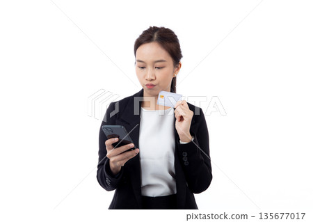 Portrait young asian businesswoman holding credit card and smartphone while thoughtful isolated. Portrait young asian businesswoman holding credit card and smartphone while thoughtful isolated. 135677017