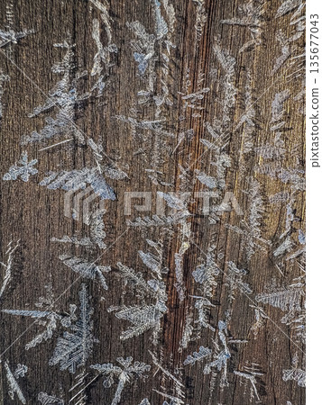 Intricate frost crystals on a rustic wooden background. 135677043