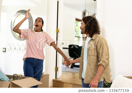 Young diverse couple unpacking moving boxes, feeling excited and joyful in new home 135677159