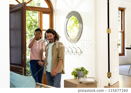 Young diverse couple entering new home, smiling and exploring bright living room together 135677160
