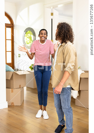 Young woman expressing excitement while unpacking boxes at new home with friend Young woman expressing excitement while unpacking boxes at new home with friend 135677166