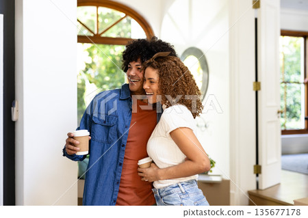 Young diverse couple enjoying coffee together at home, smiling and embracing warmly 135677178