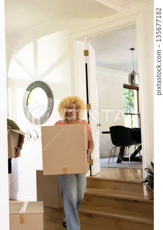 Young woman carrying moving boxes into new home, smiling with excitement Young woman carrying moving boxes into new home, smiling with excitement 135677182
