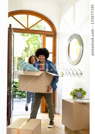 Young diverse couple carrying boxes into new home, smiling and excited for fresh start Young diverse couple carrying boxes into new home, smiling and excited for fresh start 135677195