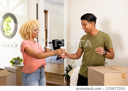 Young couple unpacking boxes and enjoying coffee in new home, smiling happily 135677203