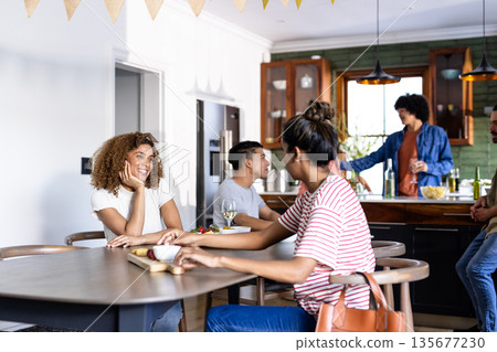 Friends enjoying conversation and drinks in modern kitchen, smiling and relaxed 135677230