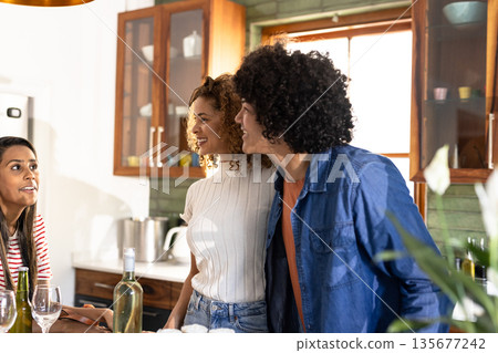 Young Diverse friends enjoying conversation and drinks in cozy kitchen setting Young Diverse friends enjoying conversation and drinks in cozy kitchen setting 135677242