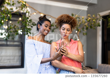 In cozy living room, women admiring engagement ring while having conversation In cozy living room, women admiring engagement ring while having conversation 135677260