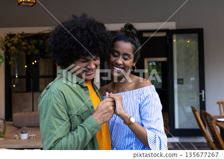 Young couple laughing and holding hands at home, enjoying joyful moment 135677267