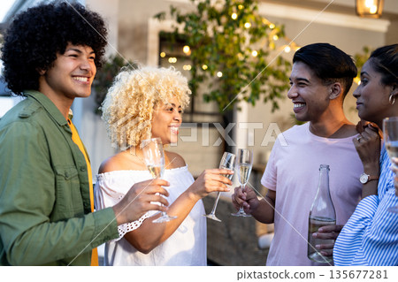 Holding champagne glasses, Diverse friends smiling together at outdoor gathering 135677281