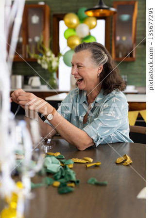 Preparing decorations for festive celebration, senior woman working joyfully at home Preparing decorations for festive celebration, senior woman working joyfully at home 135677295