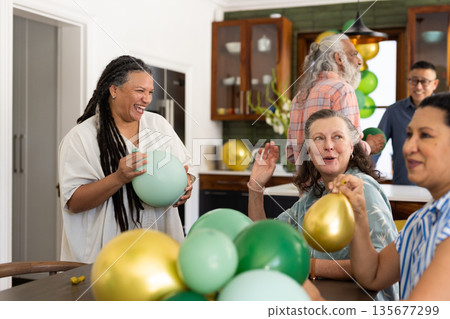 Seniors holding colorful balloons, having lively gathering with friends at home 135677299