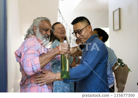 Senior friends exchanging gifts and laughter, cherishing joyful moments at home Senior friends exchanging gifts and laughter, cherishing joyful moments at home 135677300