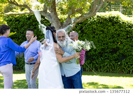 Hugging bride outdoors, senior man holding bouquet, celebrating senior wedding day Hugging bride outdoors, senior man holding bouquet, celebrating senior wedding day 135677312