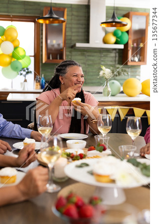 At party, senior woman having cupcake and chatting with friends At party, senior woman having cupcake and chatting with friends 135677344