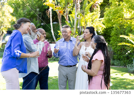 Group of seniors enjoying outdoor celebration, laughing and toasting with drinks 135677363