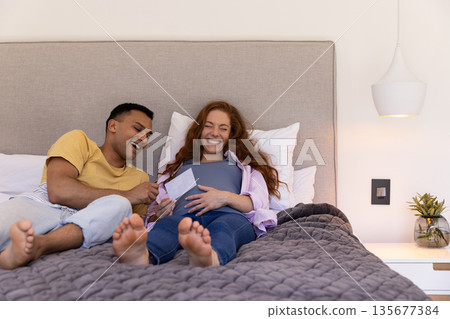 Young couple relaxing on bed, laughing and enjoying time together at home Young couple relaxing on bed, laughing and enjoying time together at home 135677384