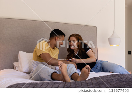 Young couple relaxing on bed, smiling and enjoying quality time together 135677403