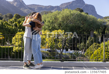 Young couple embracing on rooftop with scenic mountain view in background Young couple embracing on rooftop with scenic mountain view in background 135677405